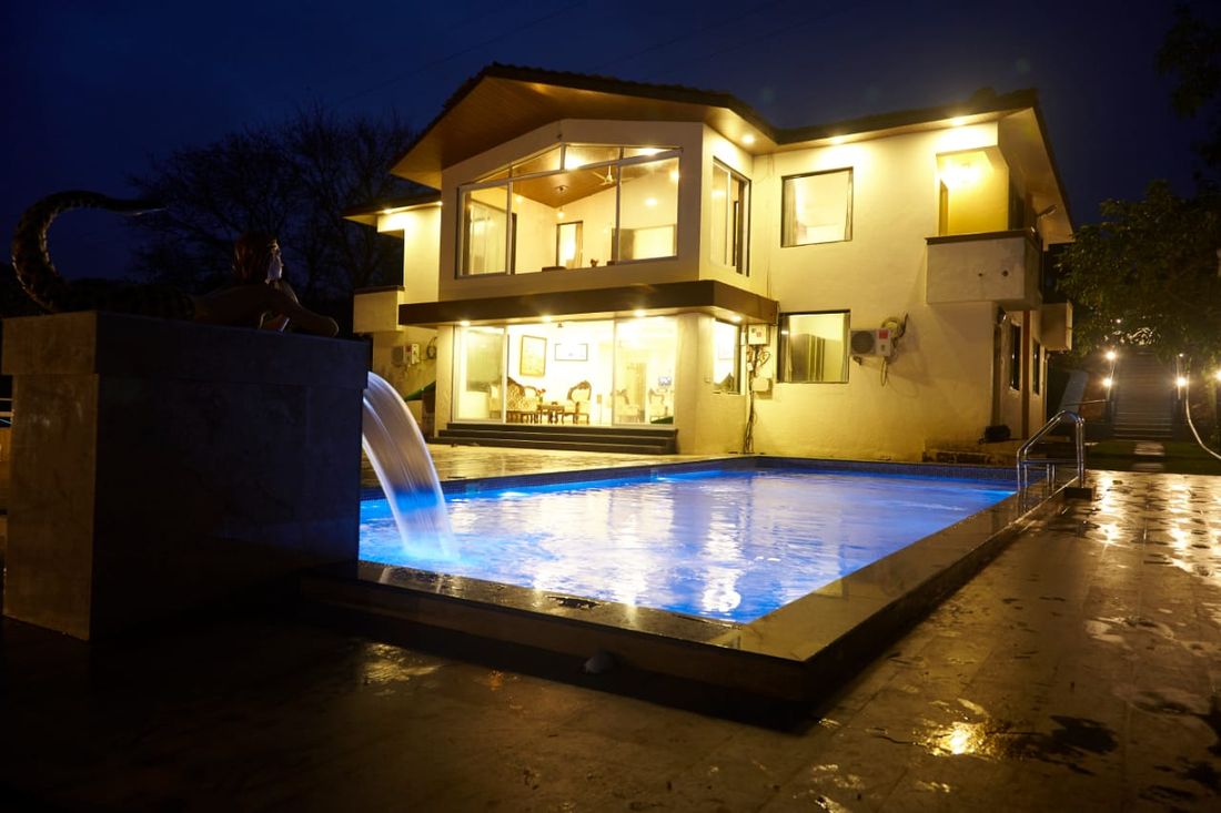 Manas Bungalow lit at night, reflected in the pool